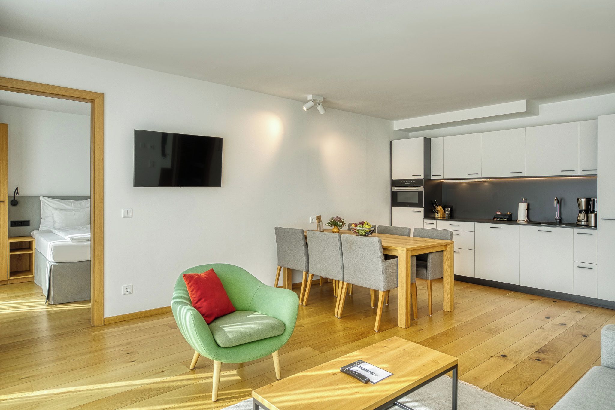 Un espacio habitable moderno con comedor, cocina y televisor montado en la pared.