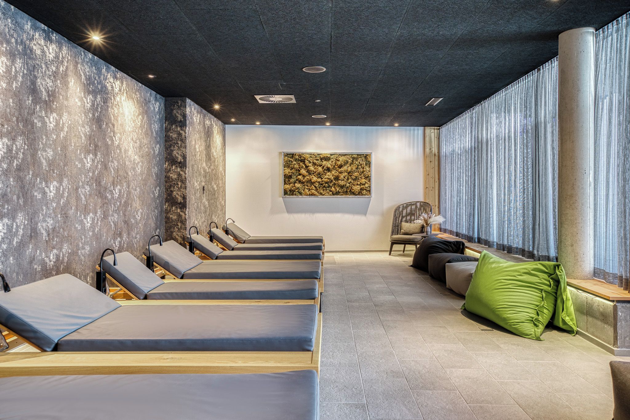 A spa room with multiple massage tables, a large abstract painting, and a view of the outdoors.