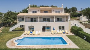 Um edifício de dois andares com piscina e espreguiçadeiras.