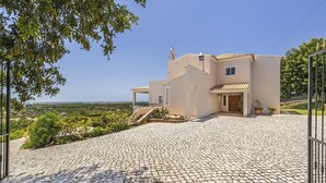Uma casa moderna com calçada pavimentada e vista para o campo.