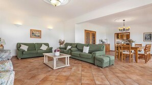 Uma sala de estar ampla com um sofá seccional grande, uma mesa de centro e um espaço de jantar com móveis de madeira.