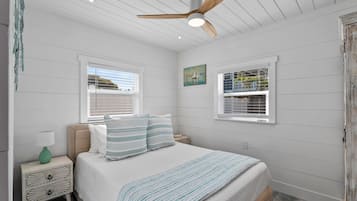 Une chambre à coucher avec un lit, une table de chevet, une lampe et un ventilateur de plafond.