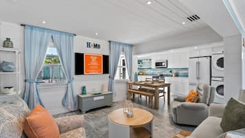 Un salon moderne comprenant un coin repas, une cuisine et un espace buanderie.