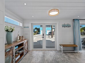 A modern interior with a bench, a door leading outside, and a wall with surfboard decorations.