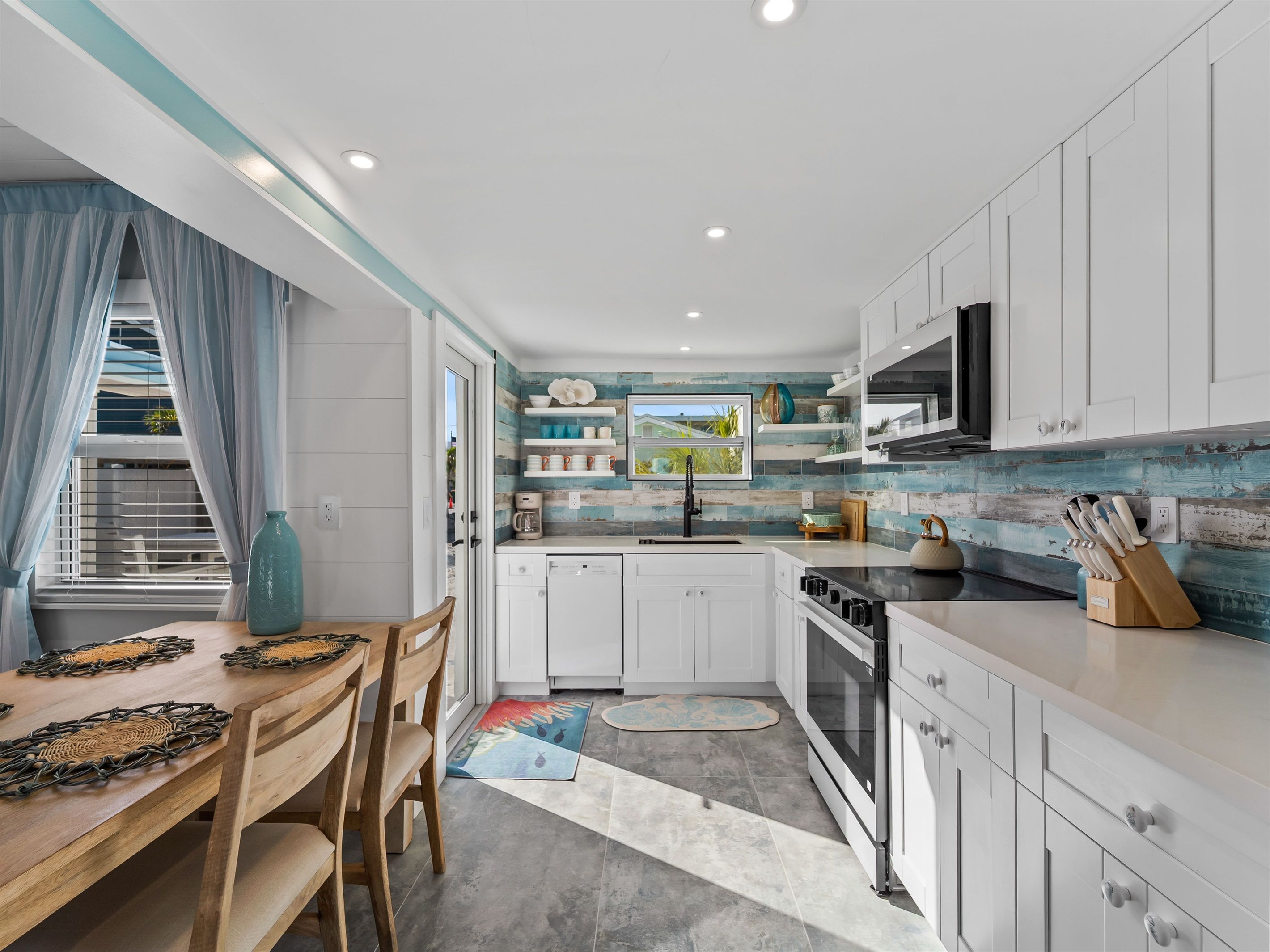A modern kitchen with white cabinets, a built-in oven, and a dining area with a wooden table and chairs.