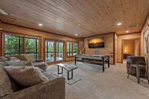 A cozy room with a pool table, comfortable seating, and large windows offering a view of the outdoors. - Fire on the Mountain - Mountain Views | 3 Levels of Decks | Outdoor Fireplaces | Hot Tub | Game Room (Mineral Bluff)