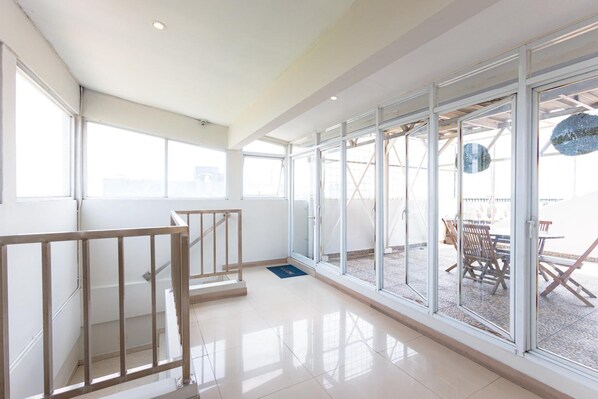 Un interior espacioso con ventanas amplias, una escalera y vistas al patio exterior.