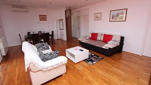 A living room with a sofa, a chair, a coffee table, and a dining table. - Apartment Suzana (Rovinj)