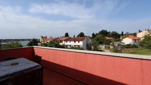 A balcony with a table and chairs, overlooking a residential area with houses and a body of water. - Apartment Suzana (Rovinj)