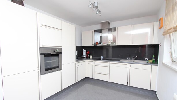 A modern kitchen with white cabinets, a black countertop, and a stainless steel oven. - Apartment Suzana (Rovinj)