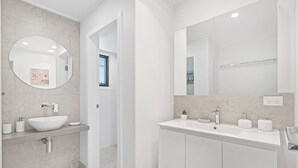 A modern bathroom with a white sink, mirror, and vanity. - Seahaven 1 close to Shoal Bay Beach (Shoal Bay)