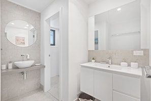 Een moderne badkamer met een wit wastafelmeubel, spiegel en wastafel.