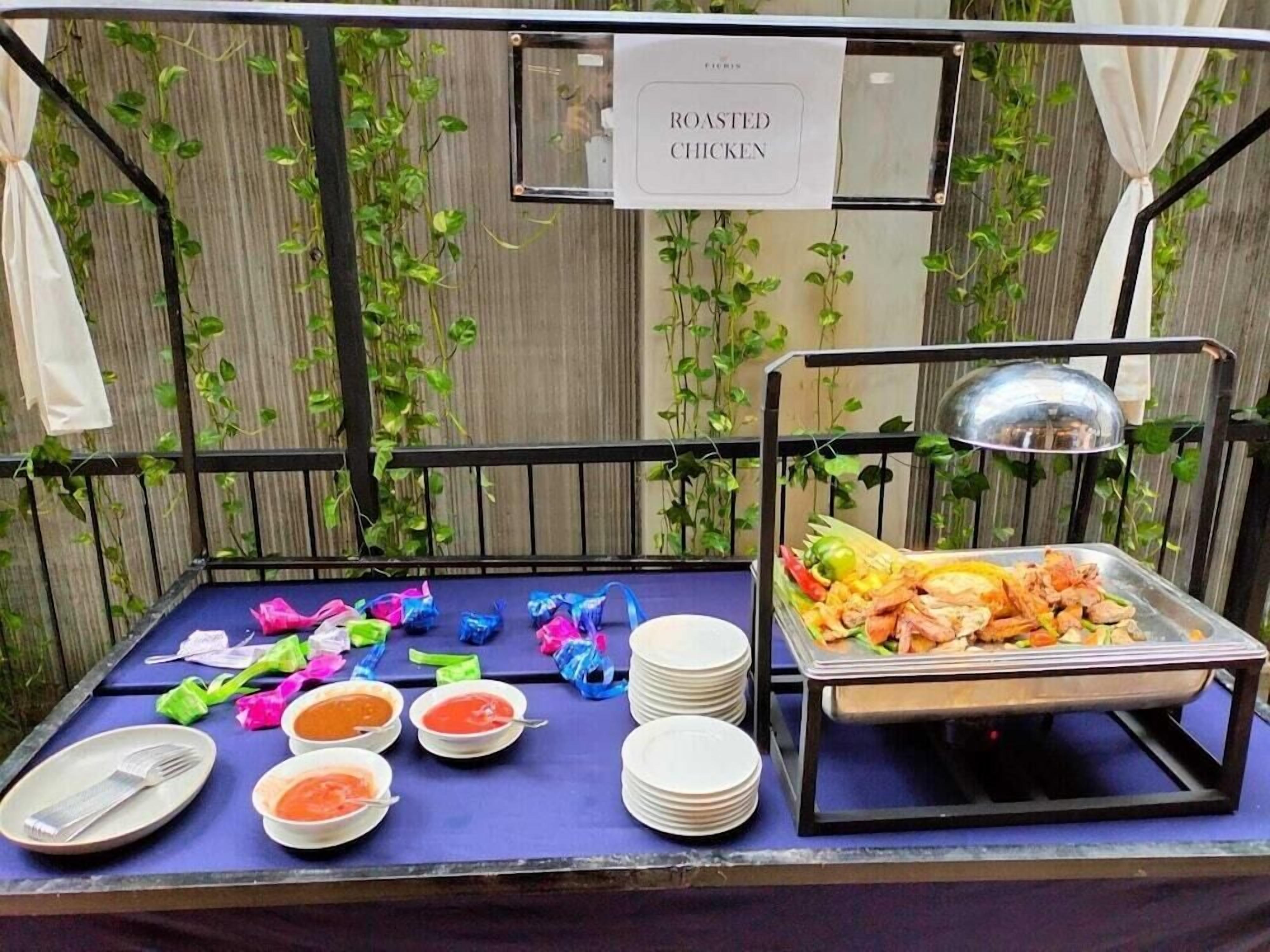 Een buffettafel met een bord waarop 'ROASTED CHICKEN' staat, en diverse gerechten, waaronder een schaal met zeevruchten.