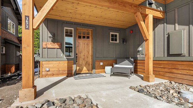 Una cabaña con porche de madera, una puerta, una ventana y un letrero que dice "Big Bear Cabin".