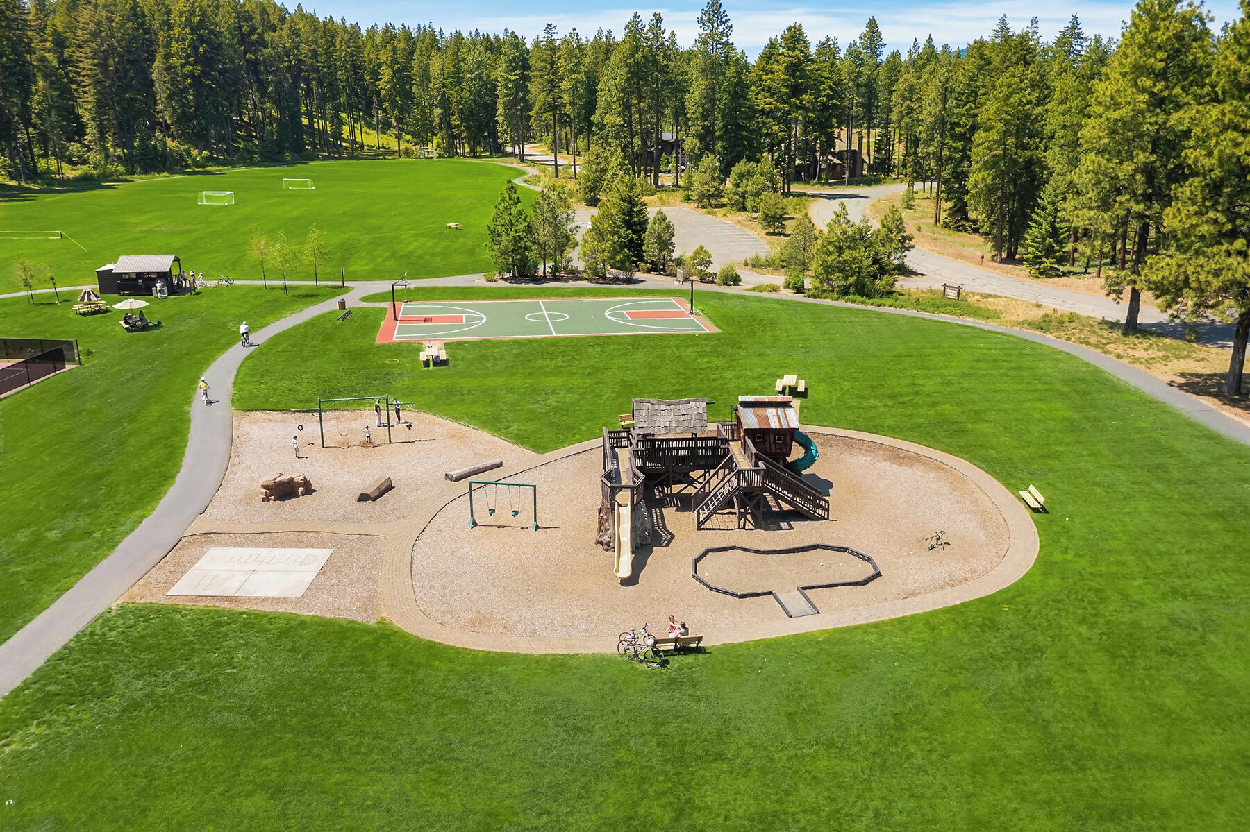 An aerial view of a park with a soccer field, playground, and walking paths.