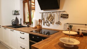 Una cocina moderna con encimera de madera, horno integrado y placa de inducción negra.