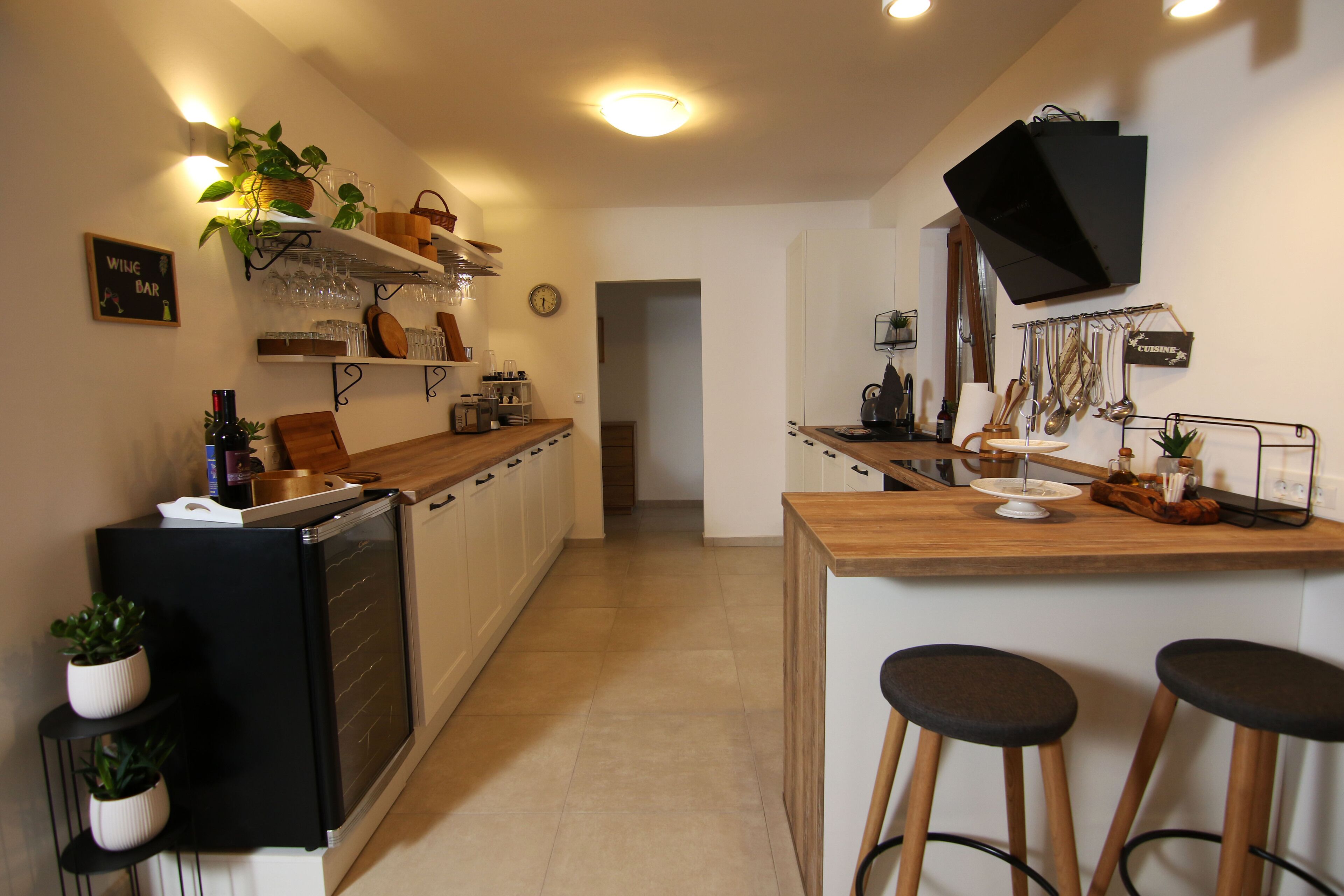 A modern kitchen with a wooden countertop, bar stools, and a built-in oven.