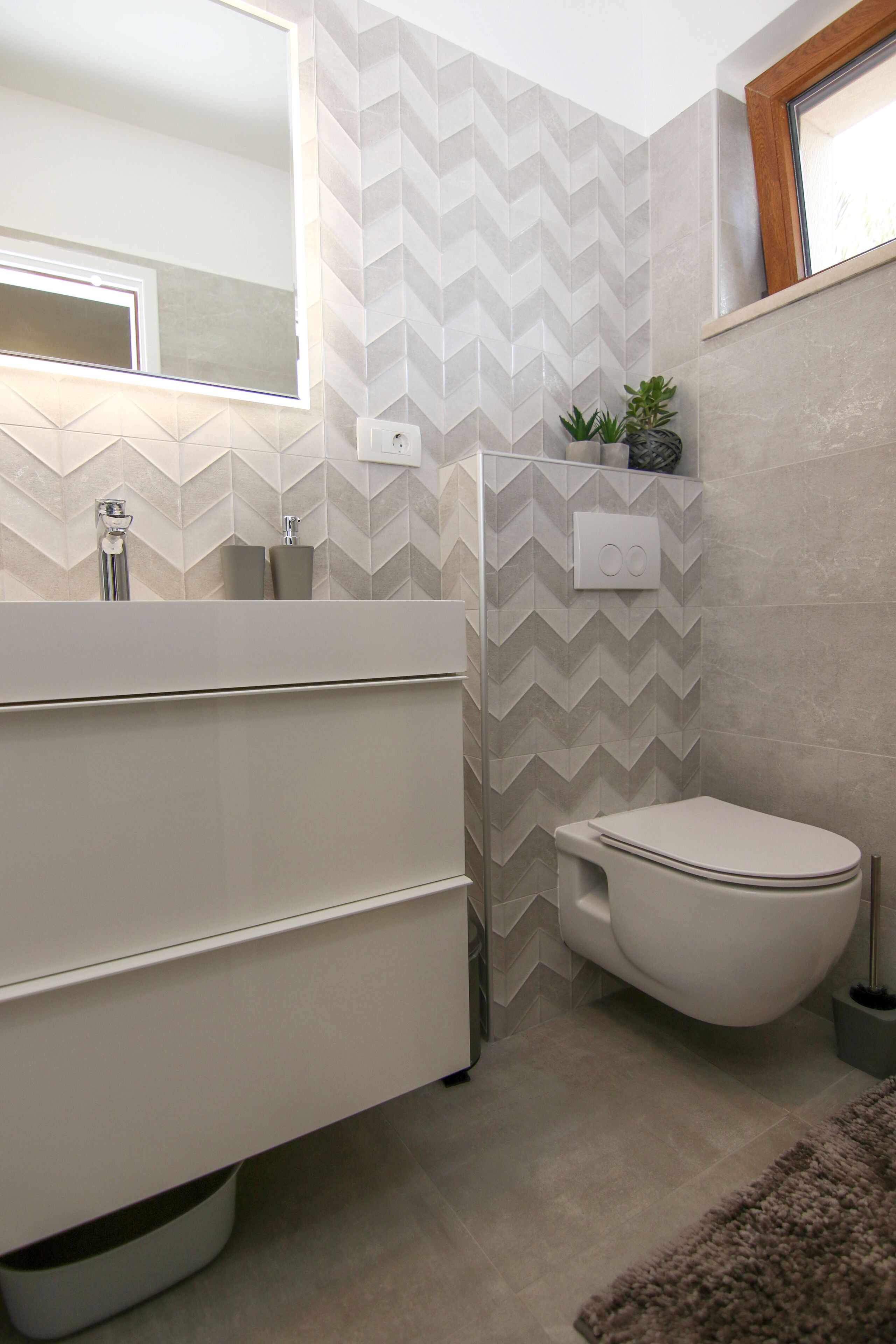 A modern bathroom with a white vanity, a toilet, and a mirror.