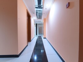 Un pasillo con piso reflectante, paredes pintadas en un tono claro y una puerta al final.