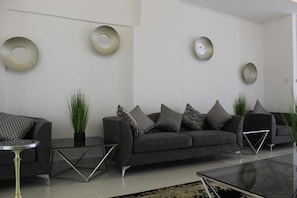 A modern living room with a grey sofa, decorative wall rings, and a glass coffee table.