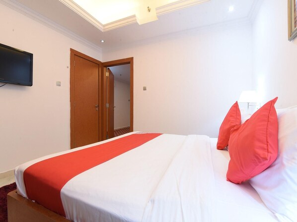 A hotel room with a bed, a television mounted on the wall, and a door leading to another room. - Mirage Hotel Dibba Fujairah (Dibba)