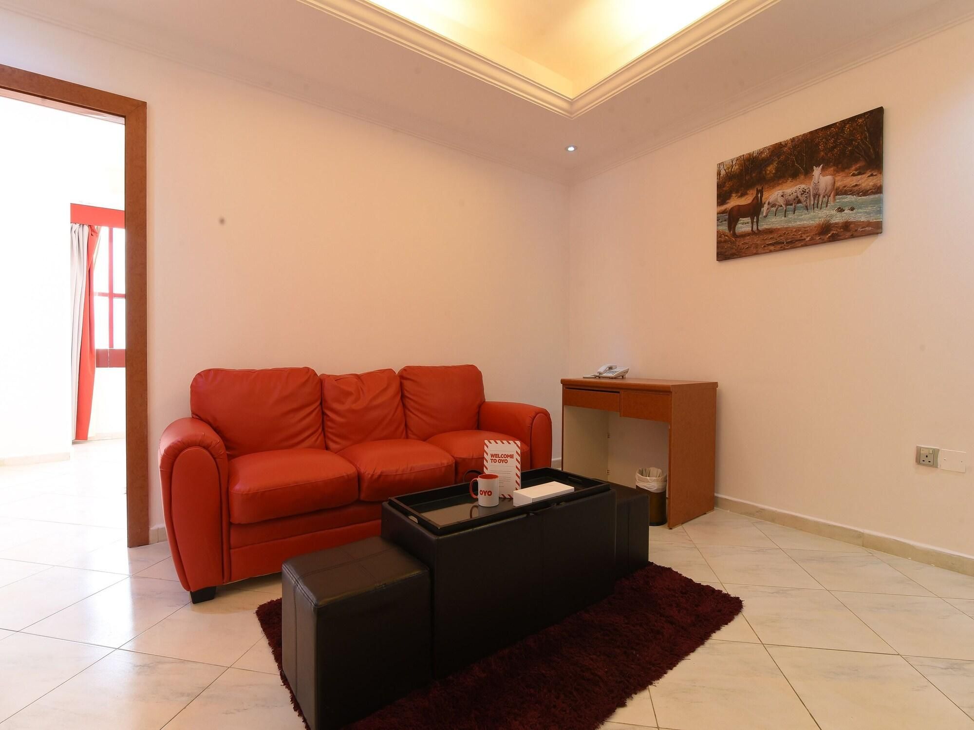 A living room with a red sofa, a black coffee table, and a painting on the wall.