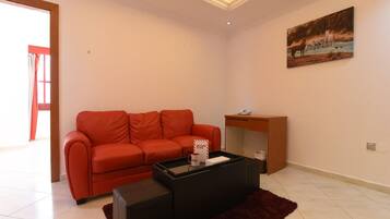 A living room with a red sofa, a black coffee table, and a painting on the wall.