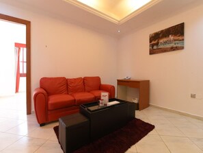 A living room with a red sofa, a black coffee table, and a painting on the wall.