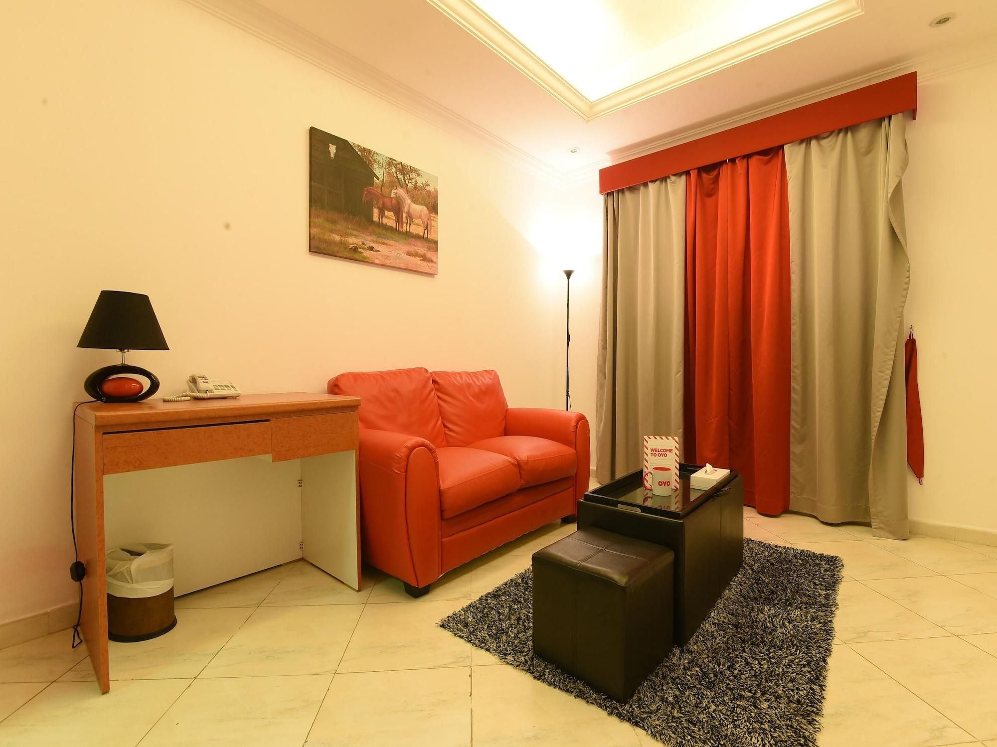 A compact living space with a sofa, a desk, a lamp, and a painting on the wall.