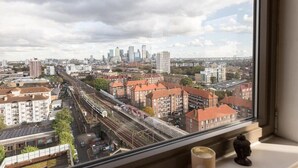A cityscape view from a window overlooking a railway line and residential buildings. - Stunning East London 2 Bed Apartment With Views (London)