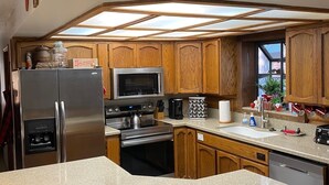 A kitchen with wooden cabinets, stainless steel appliances, a large island, and a skylight. - Private Mountain True Log Cabin Retreat with 2 Master Bedrooms (Strawberry)