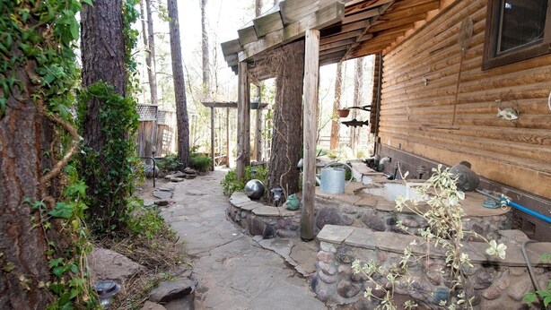 A rustic wooden cabin with a stone pathway leading to a covered outdoor area with a hanging pot. - Private Mountain True Log Cabin Retreat with 2 Master Bedrooms (Strawberry)