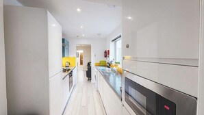 A modern kitchen with white cabinetry, a stainless steel oven, and a yellow countertop. - Perfect for contractors, 4-bedrooms, sleeps 7! (Crewe)