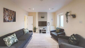A living room with two sofas, a TV, and a plant. - Perfect for contractors, 4-bedrooms, sleeps 7! (Crewe)