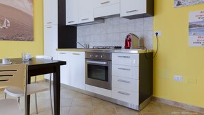 Cuina amb armaris blancs, forn d'acer inoxidable i torradora vermella.
