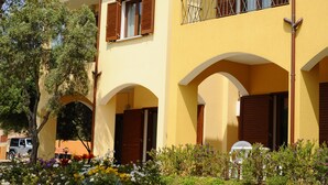 Un edifici groc amb portals arquejats i un balcó.