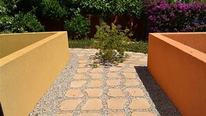 Un camí pavimentat amb pedres de forma irregular, delimitat per dues parets amb superfície rugosa.