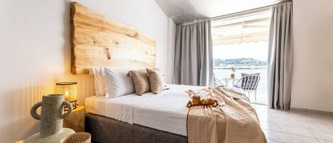 A bedroom with a large bed, a wooden headboard, a bedside lamp, and a view of the outdoors through a window.