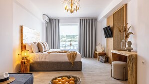 A modern hotel room with a large bed, a wooden side table, a TV, and a view of the outdoors. - Casa Blue Marine (Skiathos)
