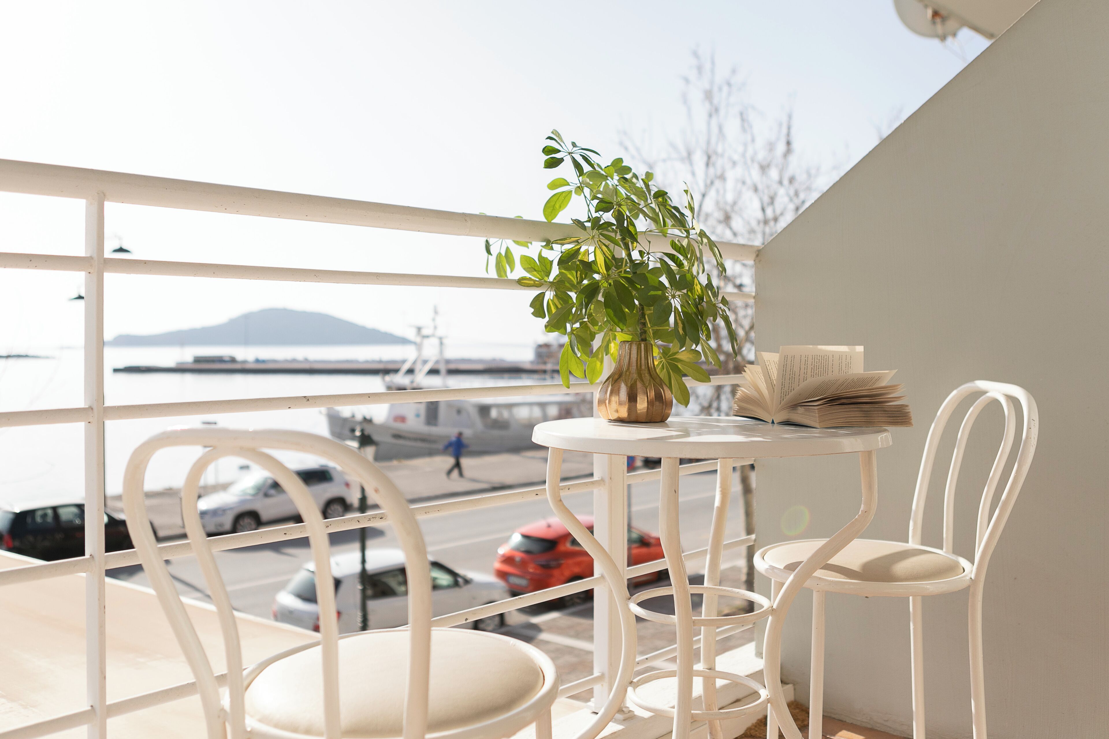 Un balcon donnant sur une étendue d’eau, avec une plante et une table entourée de chaises.
