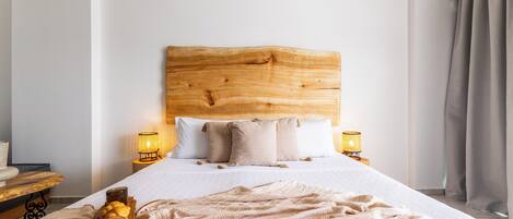 Un lit bien fait, avec une tête de lit en bois, deux lampes de chevet et une table de chevet avec une lampe.