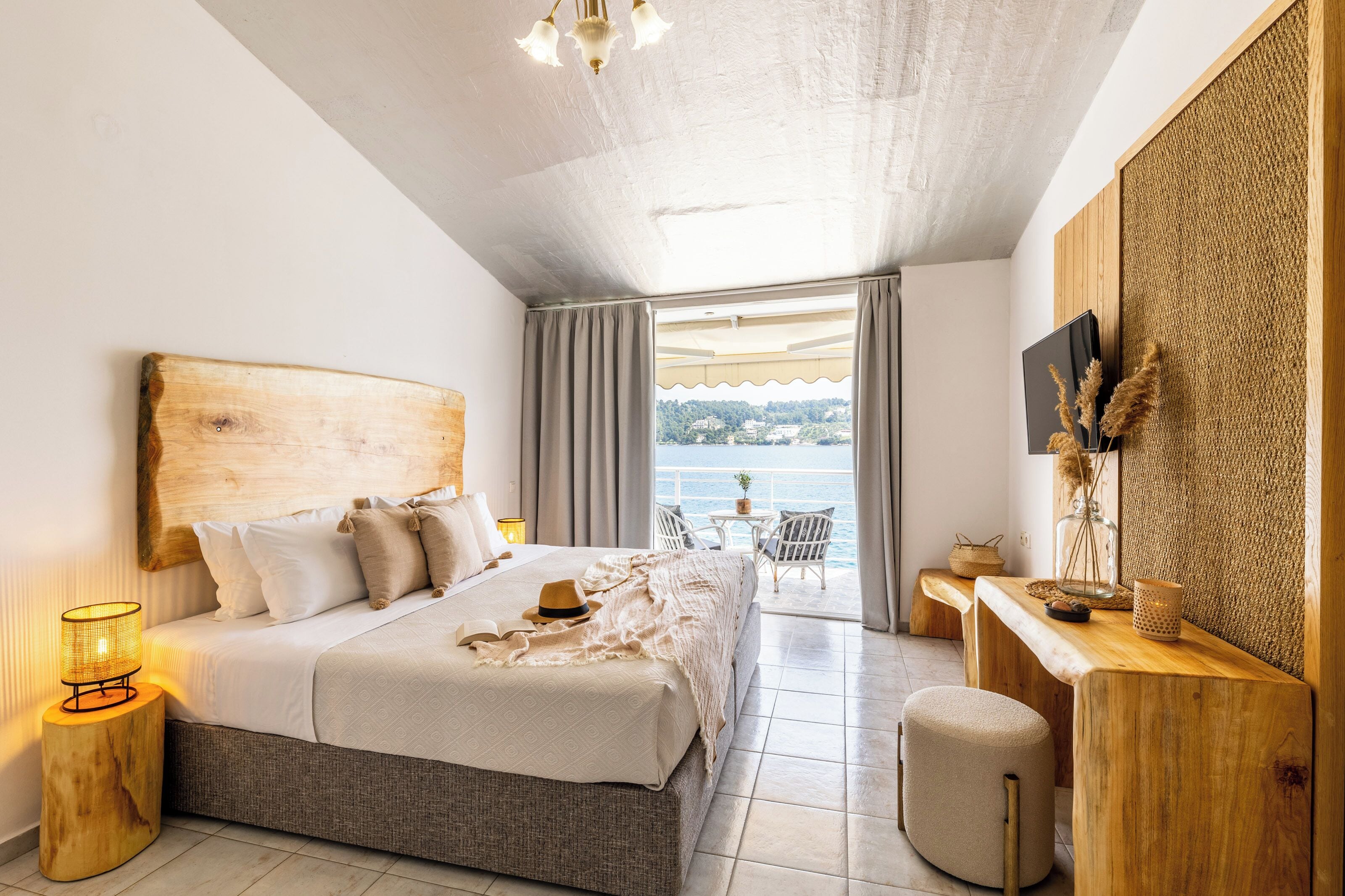 A bedroom with a large bed, a desk, and a view of the sea.