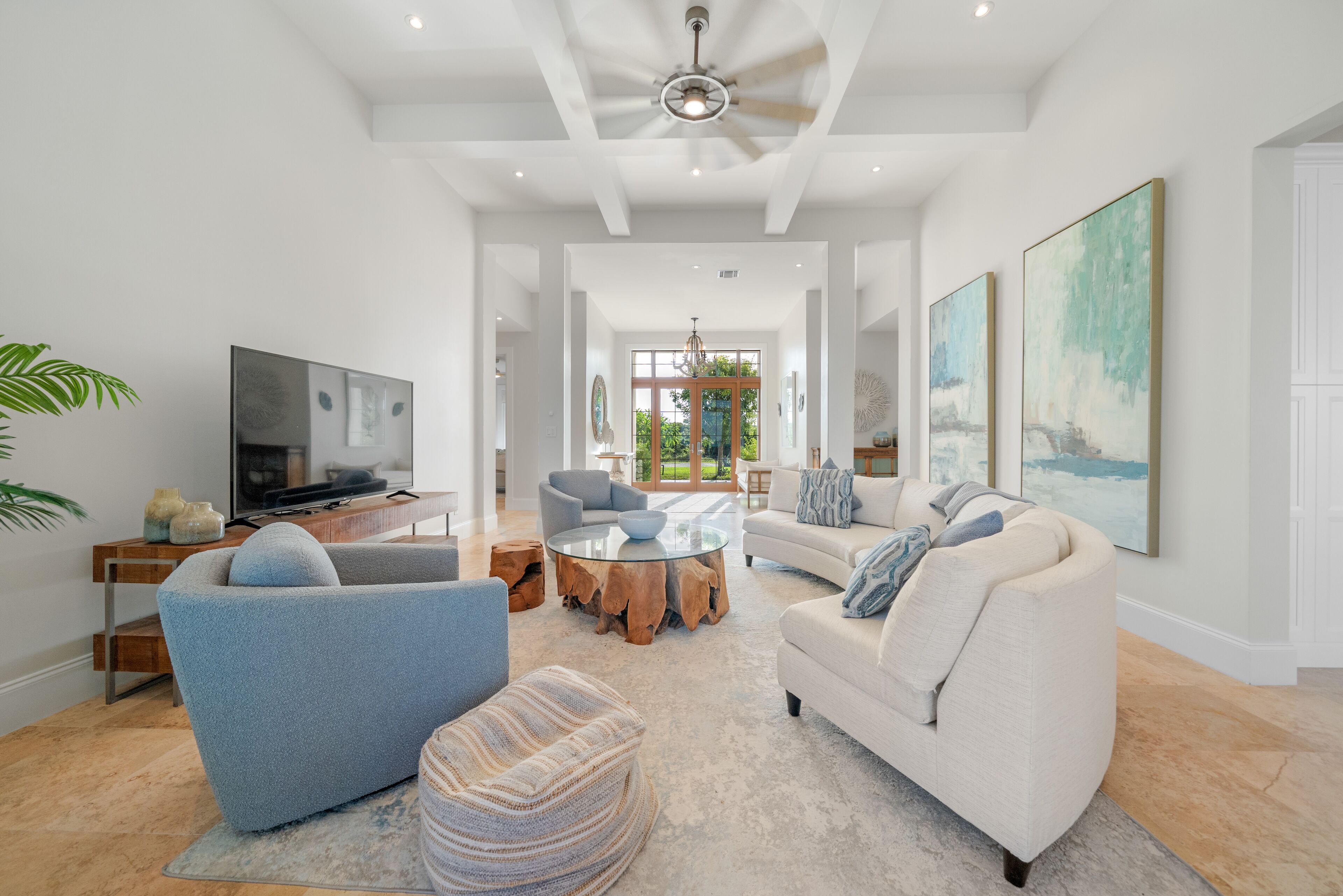 A spacious living room with a large TV, comfortable seating, and artwork on the walls.