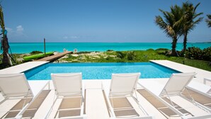 A pool with white lounge chairs facing a beach. - Seas The Day (Georgetown)