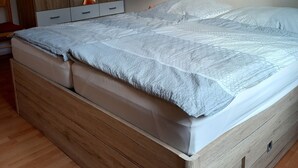 A bedroom with a wooden bed frame, a wardrobe, and a painting on the wall. - Vacation home Gerken - Apartment on the first floor (Drochtersen)