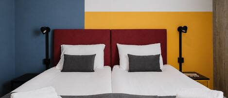 Una cama doble con dos almohadas, un cabecero rojo y dos lámparas de noche.