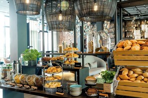 Un comptoir de boulangerie où sont exposés divers produits de boulangerie, notamment des croissants et du pain, ainsi qu’un espace dédié au café, avec une machine à café et des pots de café.
