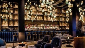 Een bar met verschillende zithoeken, waaronder banken en stoelen, en een bar met diverse flessen.