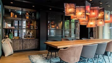 Un comedor moderno con una larga mesa de madera, sillas con cojines e iluminación colgante.