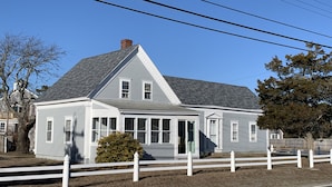 A two-story house with a gabled roof, white siding, and a front porch. - Lower County Bunk House (Dennis)